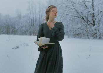 Woman Holding a Book While Standing in Snow 