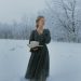 Woman Holding a Book While Standing in Snow 