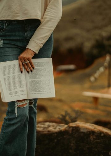A woman is holding a book on a rock