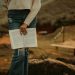 A woman is holding a book on a rock