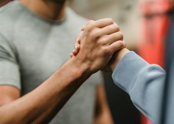 Crop sportive couple clasping hands in gym