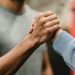 Crop sportive couple clasping hands in gym