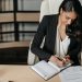Brunette Woman Sitting by Desk and Writing